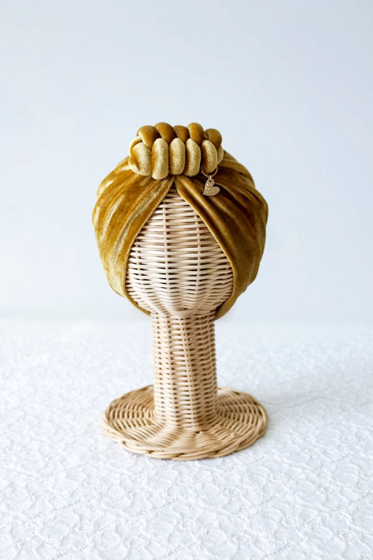 Velvet turban knot in gold color close-up view